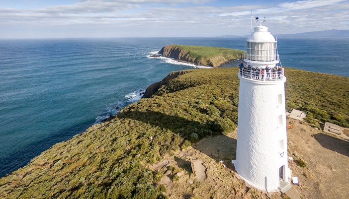 Cape Bruny Lighthouse with visitors exploring the Historic Lighthouse Museum on a guided tour.