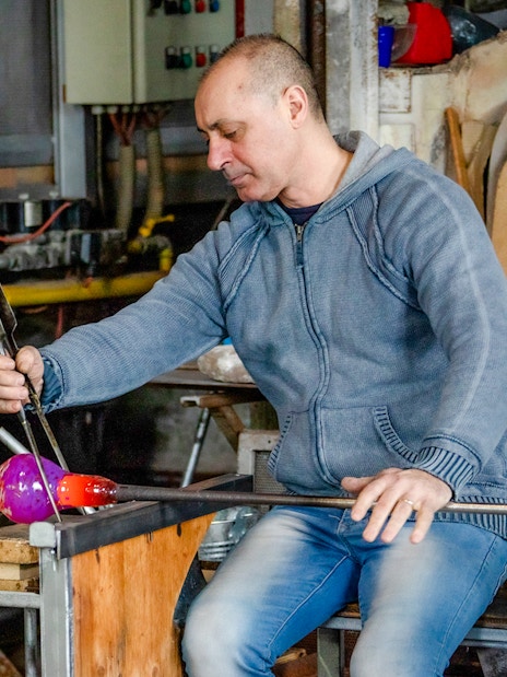 Glassblower crafting colorful glass in Murano workshop, Venice.