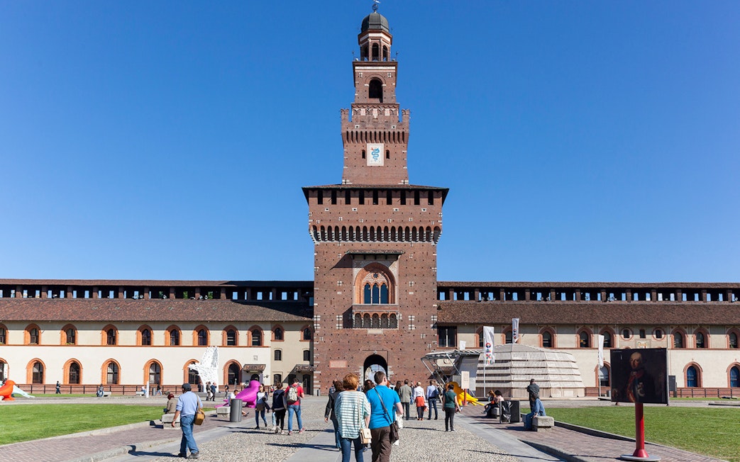 Visitors walking towards Sforza Castle courtyard in Milan, Italy.