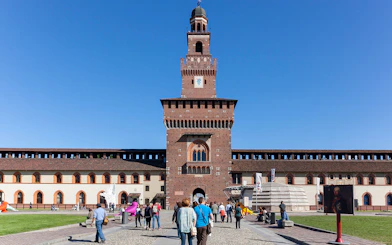 Visitors walking towards Sforza Castle courtyard in Milan, Italy.
