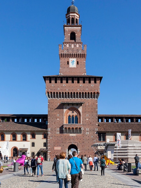 Visitors walking towards Sforza Castle courtyard in Milan, Italy.