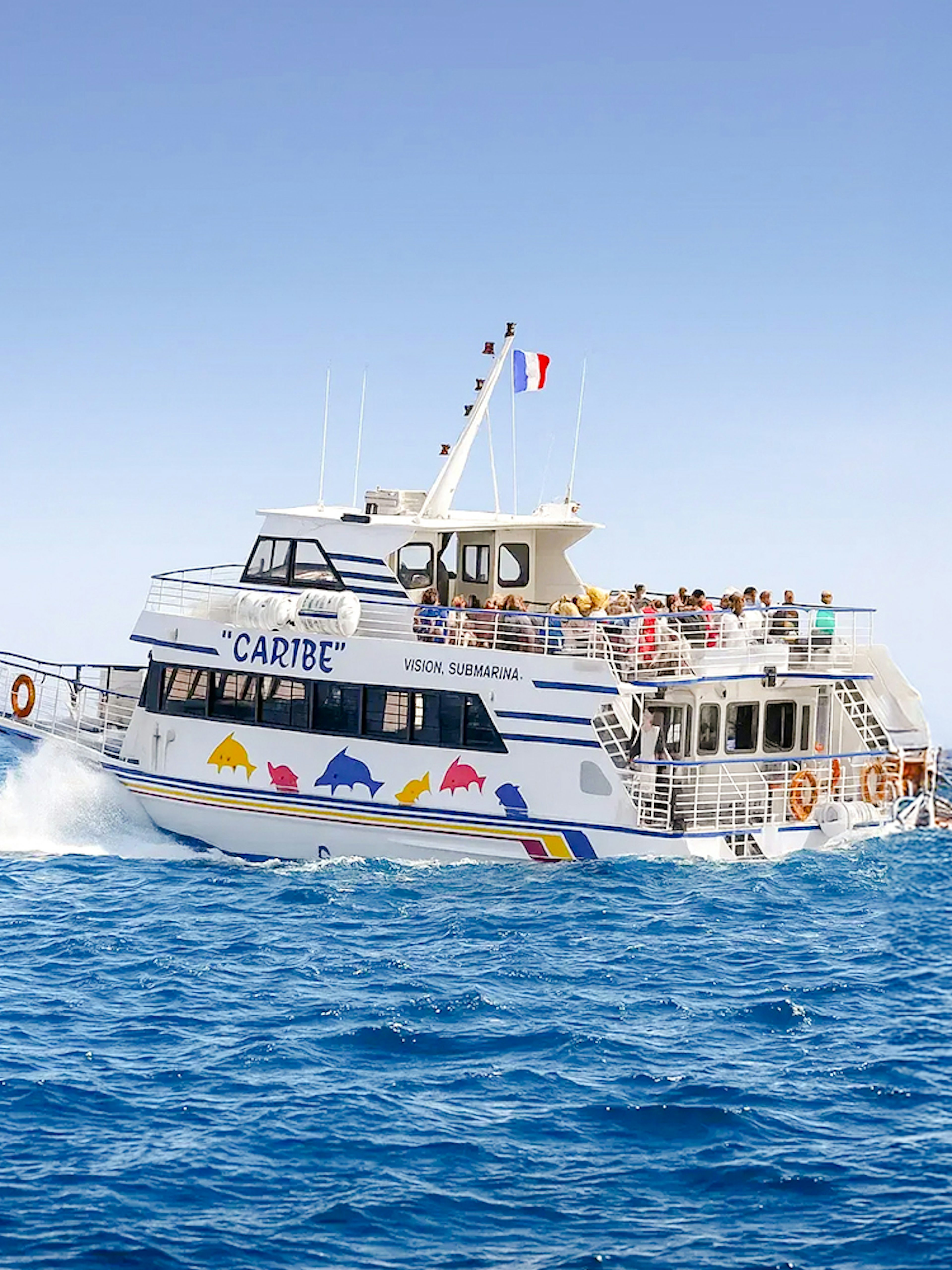 Tourists on a sightseeing cruise boat in Nice, France, with distant mountains.