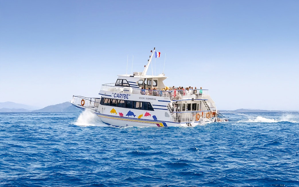 Tourists on a sightseeing cruise boat in Nice, France, with distant mountains.