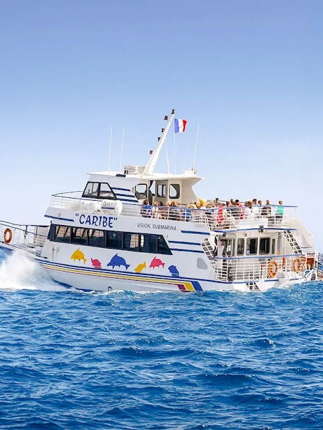 Tourists on a sightseeing cruise boat in Nice, France, with distant mountains.