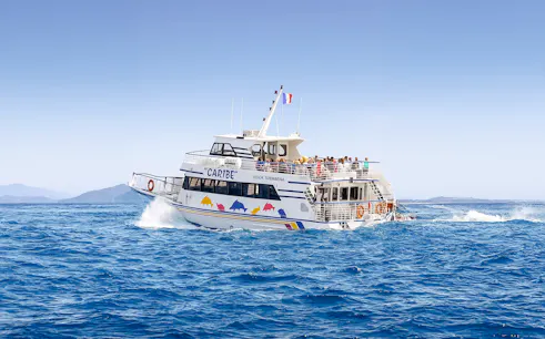 Tourists on a sightseeing cruise boat in Nice, France, with distant mountains.