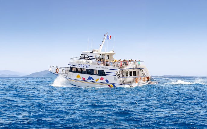 Tourists on a sightseeing cruise boat in Nice, France, with distant mountains.