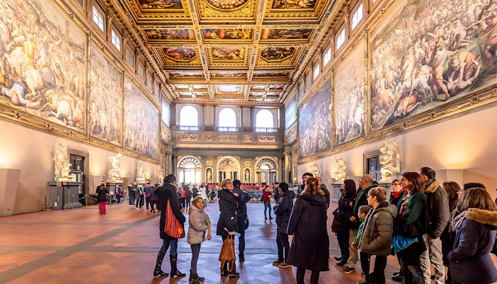 Visitors exploring the ornate hall of Palazzo Vecchio on a skip-the-line tour in Florence, Italy.