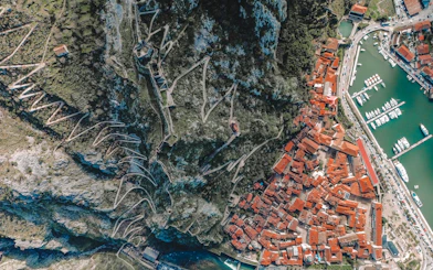 Aerial view of Kotor's red-roofed buildings and winding fortress walls near the harbor, Montenegro.