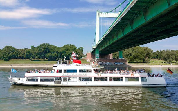 Cruise boat on the Rhine River passing under a bridge in Cologne's Old Town.