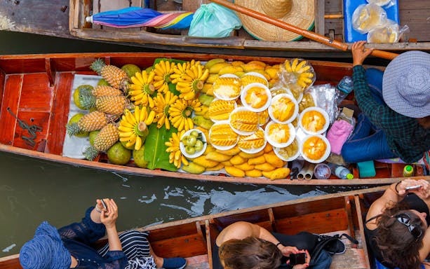 Floating market boat in Pattaya with tropical fruits like bananas and pineapples.