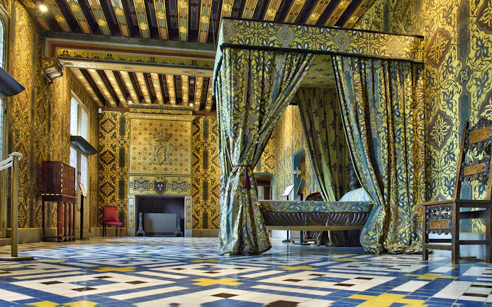 Royal Blois Castle interior with ornate bed and patterned walls.