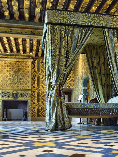 Royal Blois Castle interior with ornate bed and patterned walls.