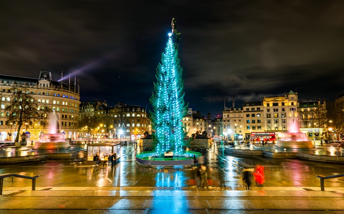 Trafalgar Square at night with Christmas tree and fountains, London, England.