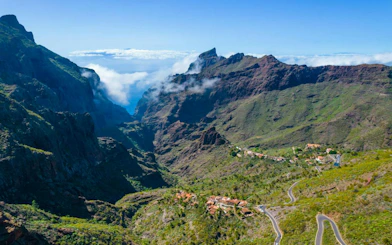 Masca Village nestled in lush green mountains, Tenerife, with winding roads and distant peaks.
