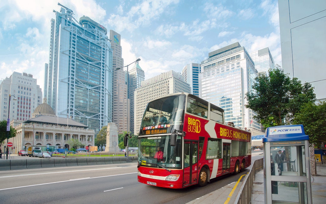 Big Bus tour in Hong Kong passing modern skyscrapers.