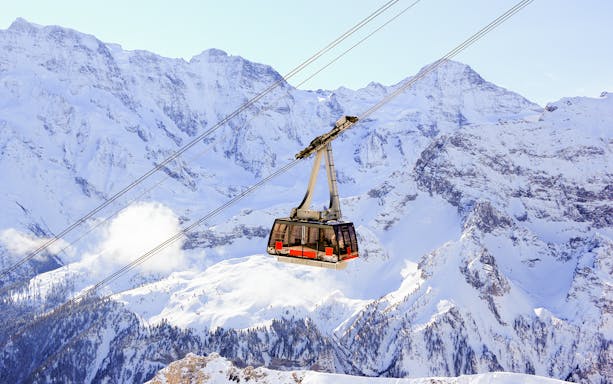 Schilthorn cable car ascending snowy mountains near Interlaken, Switzerland.