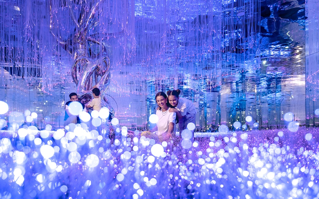 Visitors exploring Celestia inside AYA Universe with glowing lights and reflective surfaces.
