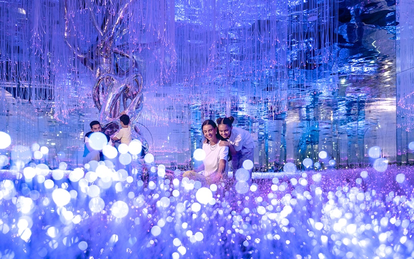 Visitors exploring Celestia inside AYA Universe with glowing lights and reflective surfaces.