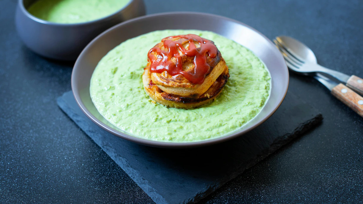 Traditional Australian pie floater with meat pie in green pea soup on black background.