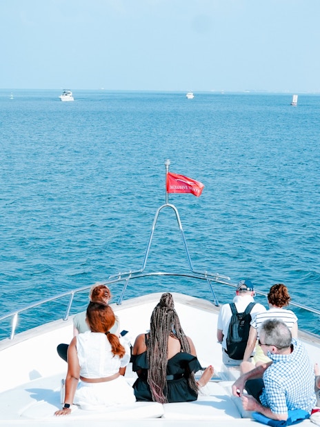 Tourists on a yacht in Dubai Harbour with Burj Al Arab in the background.