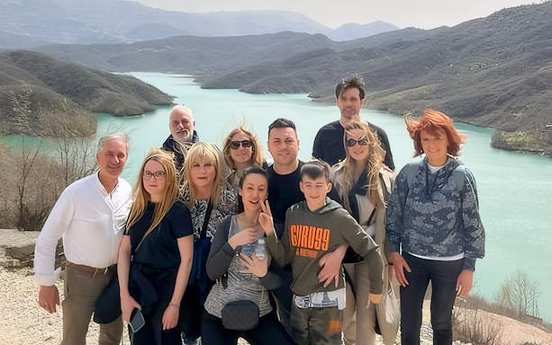 Guests hiking at Gamti Mountain with a scenic view of the lake and surrounding hills.