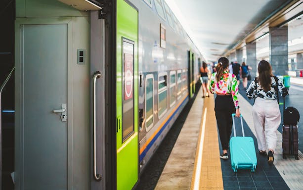 High-speed train platform in Naples with travelers and luggage.
