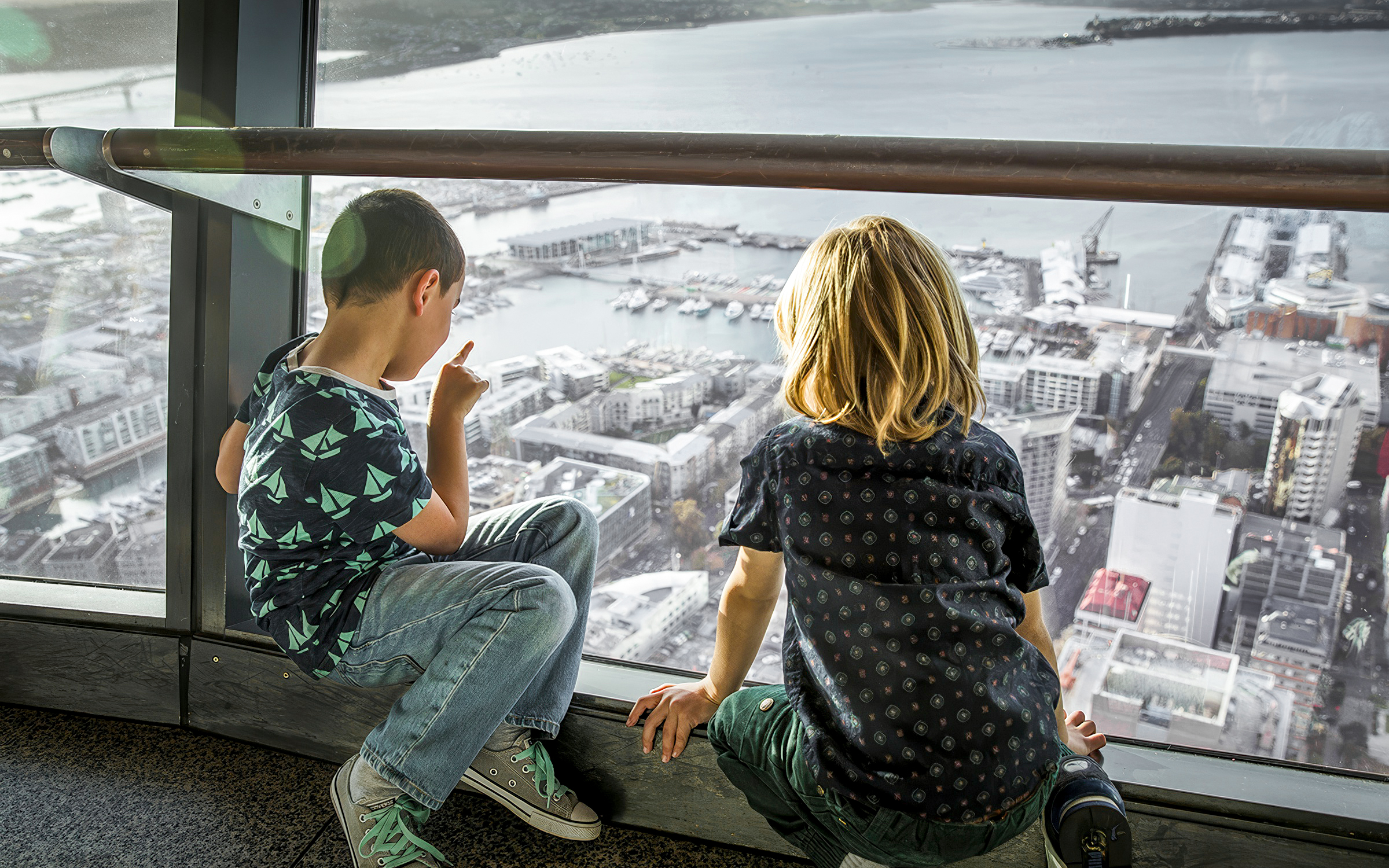 Guests on the observation deck of the Sky Tower, Auckland, overlooking the city and harbor.