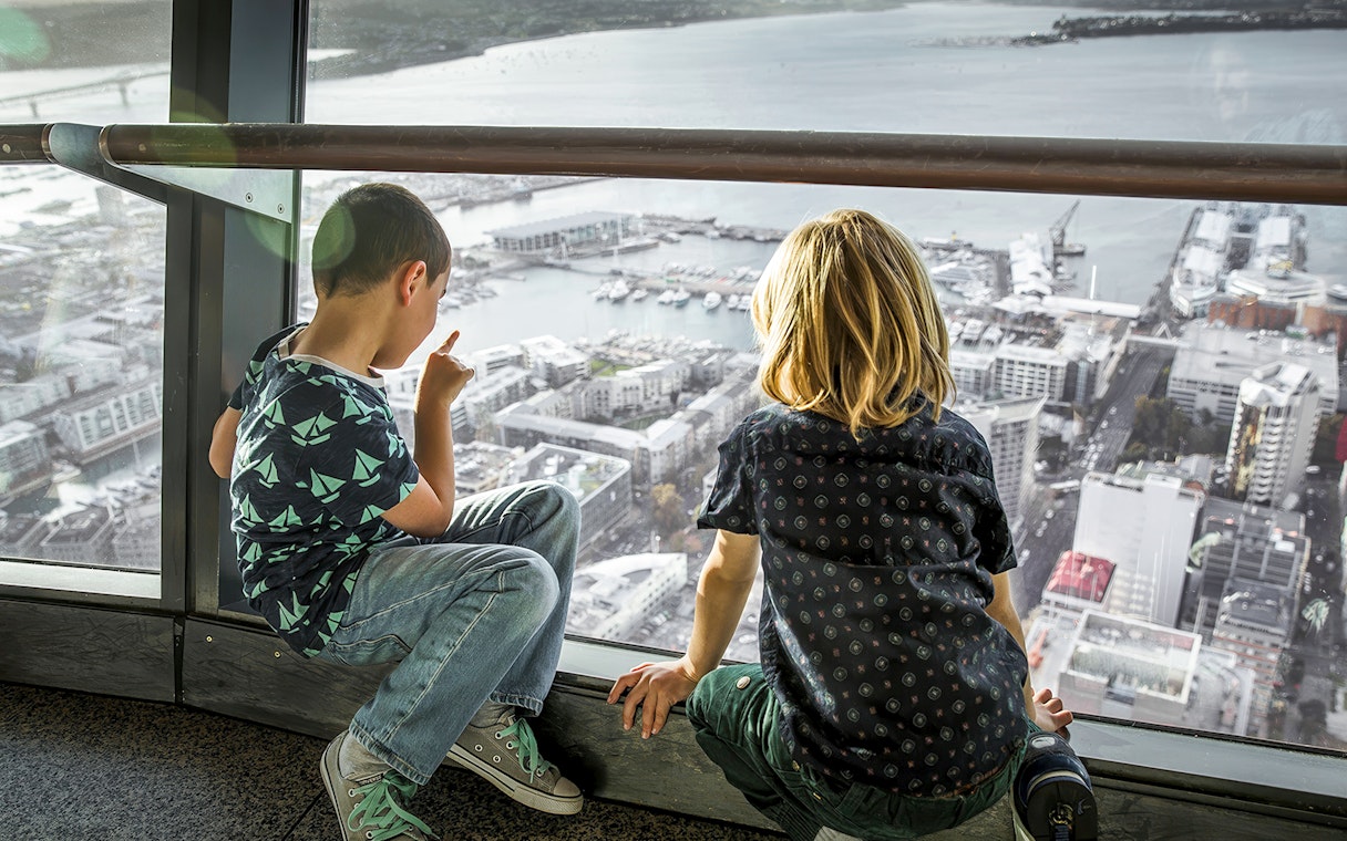 Guests on the observation deck of the Sky Tower, Auckland, overlooking the city and harbor.