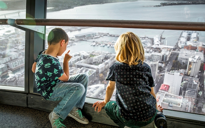 Guests on the observation deck of the Sky Tower, Auckland, overlooking the city and harbor.