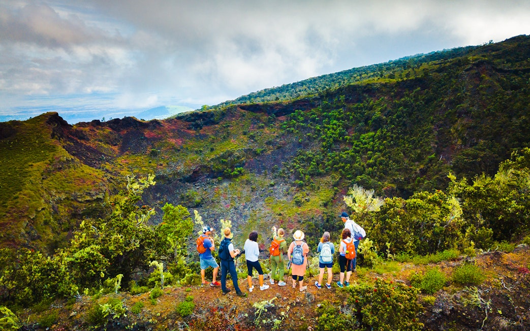 Guests observing Hualalai volcano crater with guide in Hawaii.