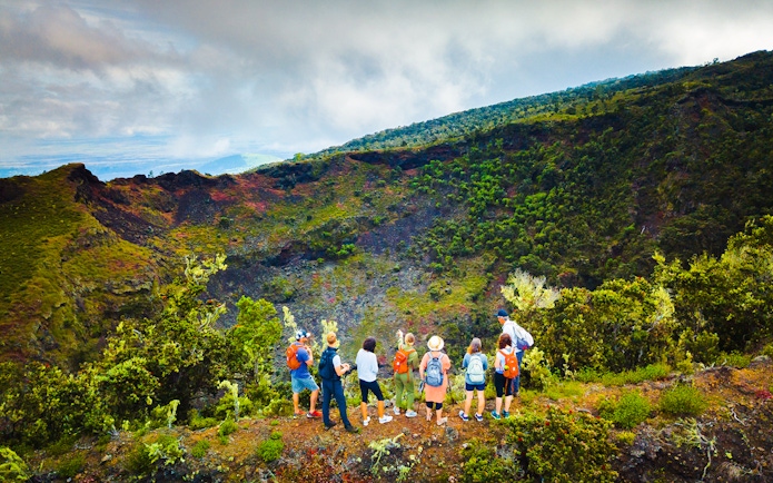 Guests observing Hualalai volcano crater with guide in Hawaii.