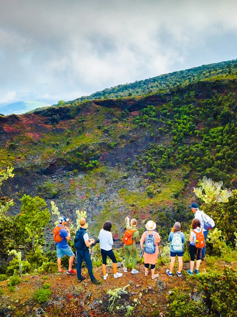 Guests observing Hualalai volcano crater with guide in Hawaii.