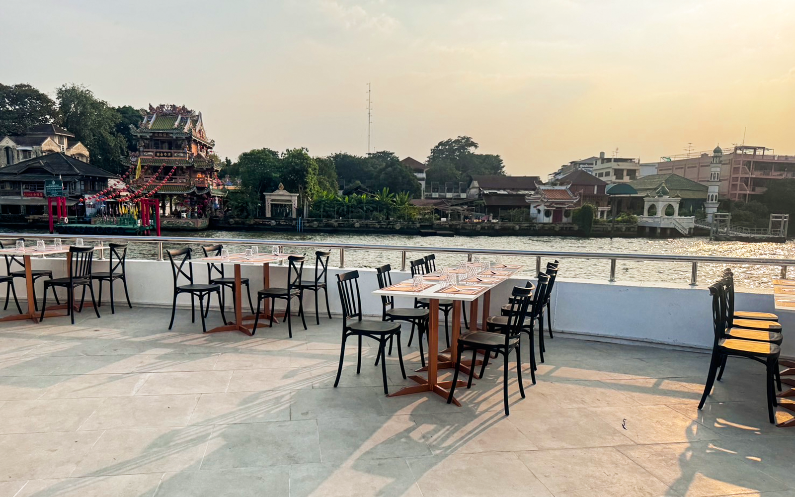 Luxury dinner cruise tables set on ICONSIAM boat with city skyline view, Bangkok, Thailand.