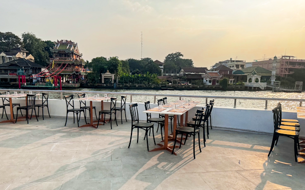 Tables set for dining on The Luxury White Dinner Cruise at ICONSIAM, overlooking the river and cityscape.