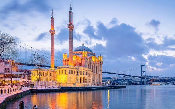 Ortakoy Mosque illuminated at dusk, viewed from the Bosphorus Dinner Cruise in Istanbul.