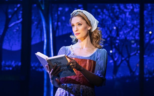 Performer reading a book on stage during "Once Upon a One More Time" show.