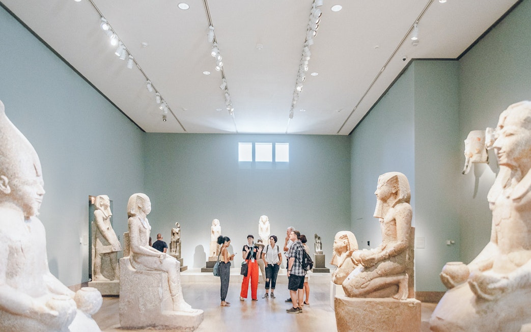 Guests viewing Egyptian sculptures at the Metropolitan Museum of Art.