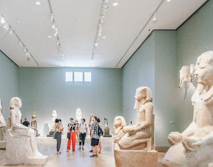 Guests viewing Egyptian sculptures at the Metropolitan Museum of Art.