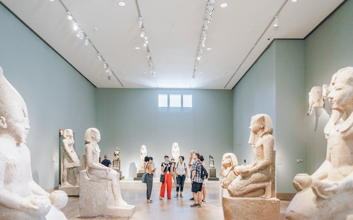Guests viewing Egyptian sculptures at the Metropolitan Museum of Art.