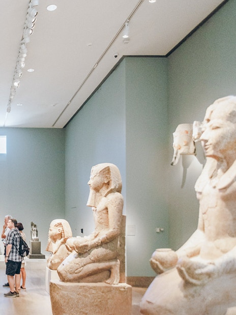 Guests viewing Egyptian sculptures at the Metropolitan Museum of Art.