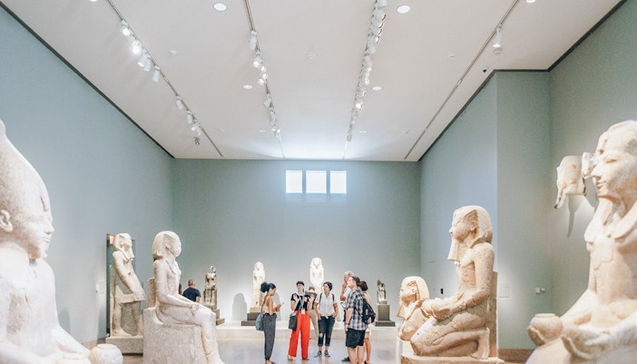 Guests viewing Egyptian sculptures at the Metropolitan Museum of Art.