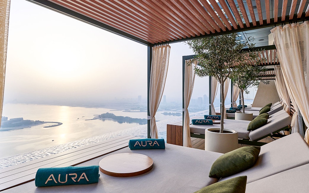 Relaxing lounge area at Rise at AURA Sky Pool with city and water views.