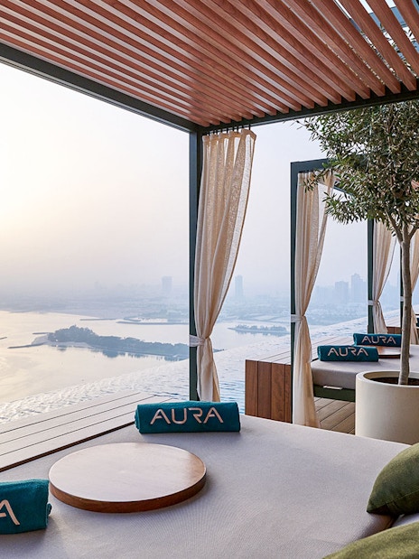 Relaxing lounge area at Rise at AURA Sky Pool with city and water views.