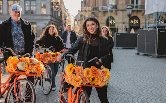 Group enjoying city bike tour with flower-adorned bicycles on cobblestone street.