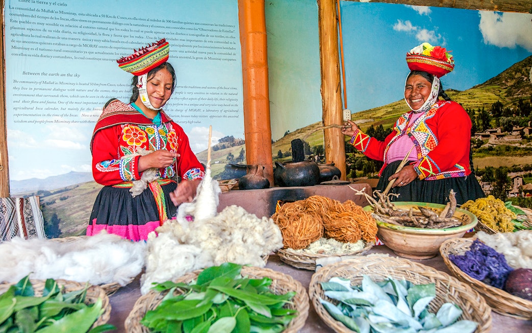 two indigenous Quechua women in traditional attire, in Chinchero, Peru, showcasing traditional textile production and natural dyeing technique