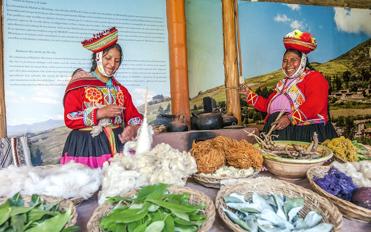 two indigenous Quechua women in traditional attire, in Chinchero, Peru, showcasing traditional textile production and natural dyeing technique