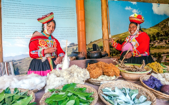 two indigenous Quechua women in traditional attire, in Chinchero, Peru, showcasing traditional textile production and natural dyeing technique