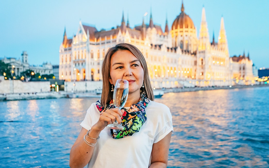 Guest with champagne on New Year’s Eve Cruise in Budapest, Hungarian Parliament in background.