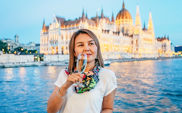 Guest with champagne on New Year’s Eve Cruise in Budapest, Hungarian Parliament in background.