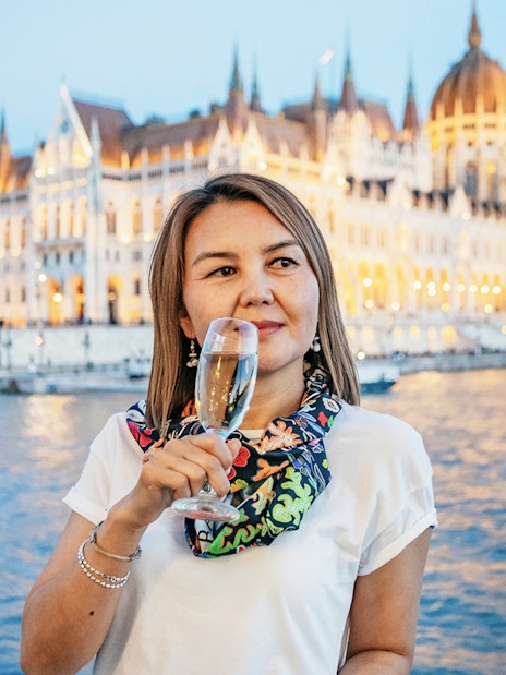 Guest with champagne on New Year’s Eve Cruise in Budapest, Hungarian Parliament in background.